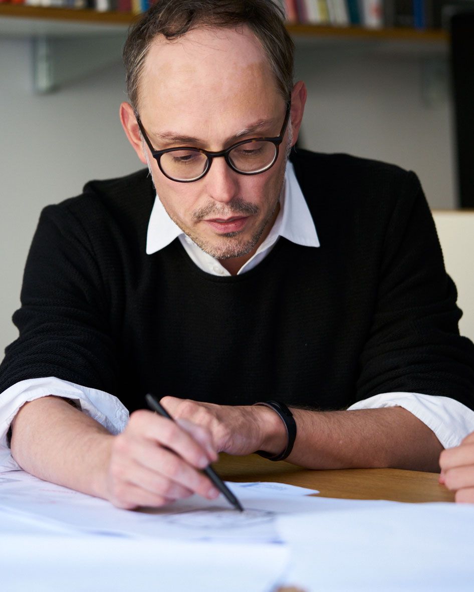 Architekt René Brouns von Schwarzgold Architekten im Austausch mit einem Kollegen über einen Grundriss